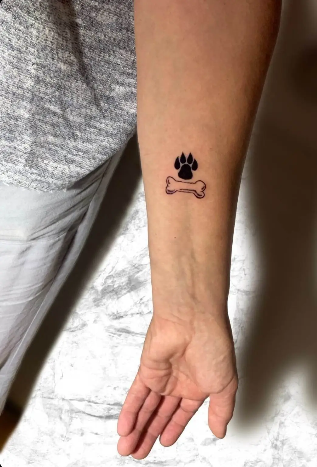 tatuaje de un hueso con la pata de un perro